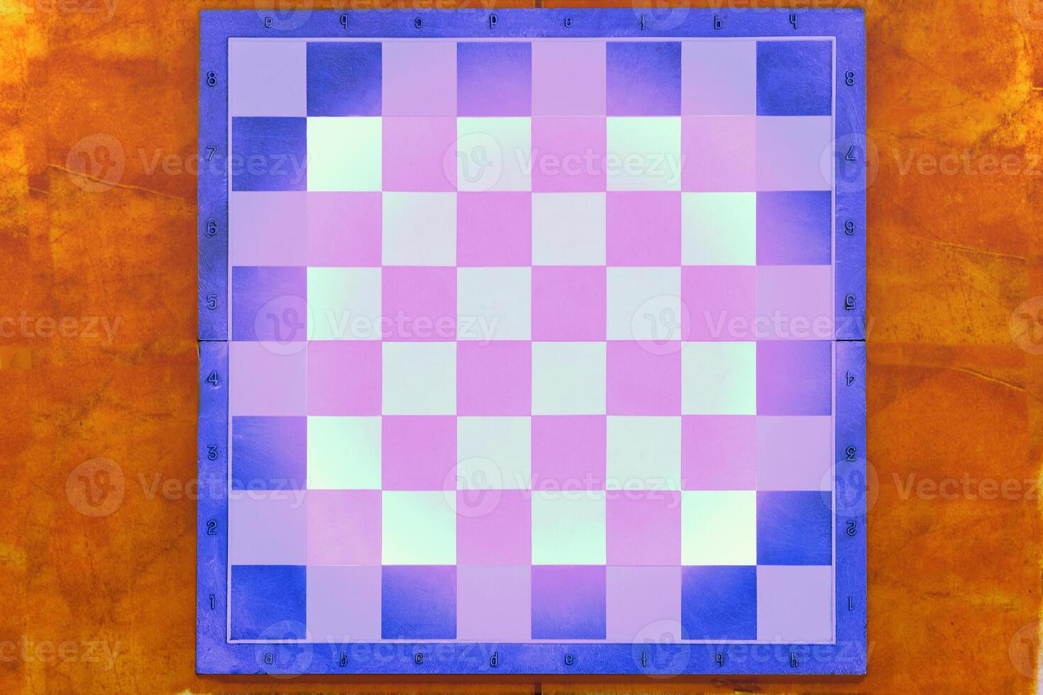 Blue chessboard with white pink on brown background with space for text photo