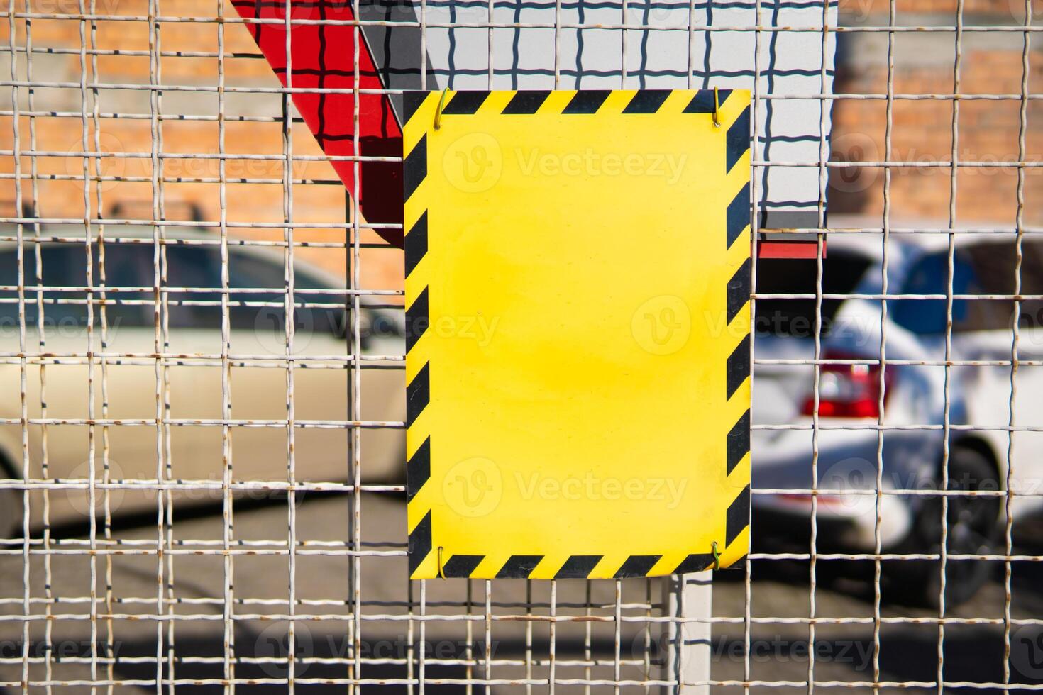 Yellow blank sign on wire fence with selective focus and blurred back photo