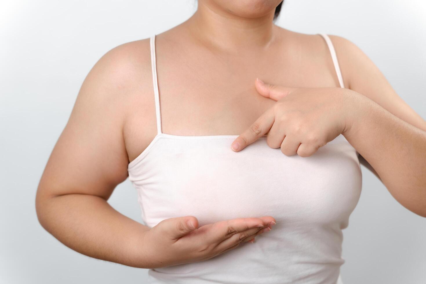 Asian woman checking lumps on her breast for signs of breast cancer on white background. photo