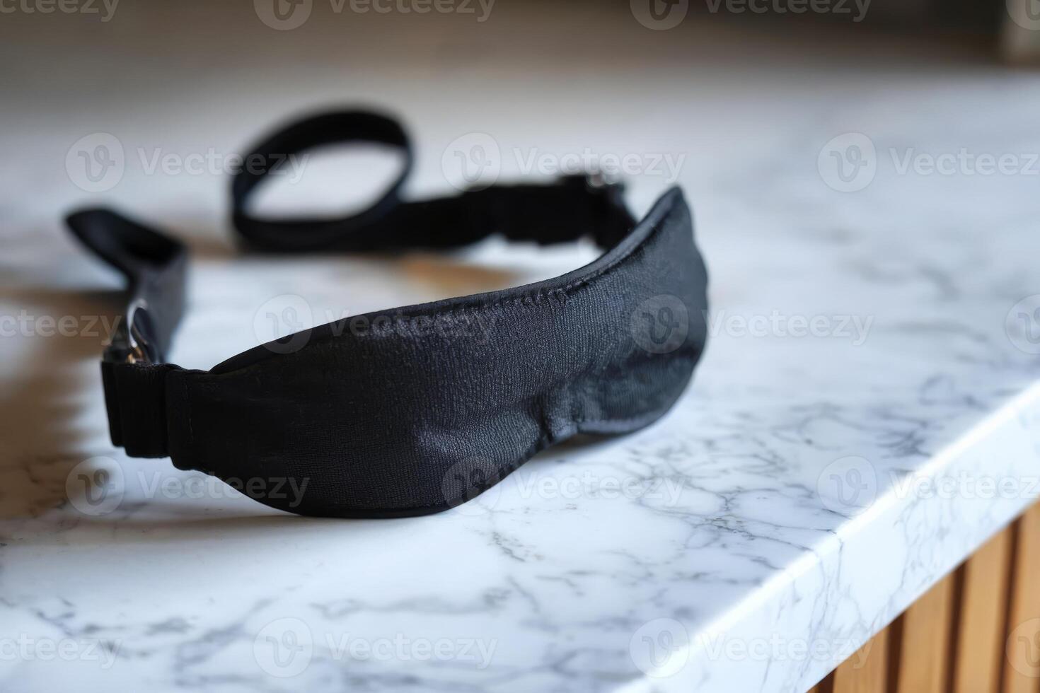 Black sleep mask on a marble countertop in a modern setting. photo