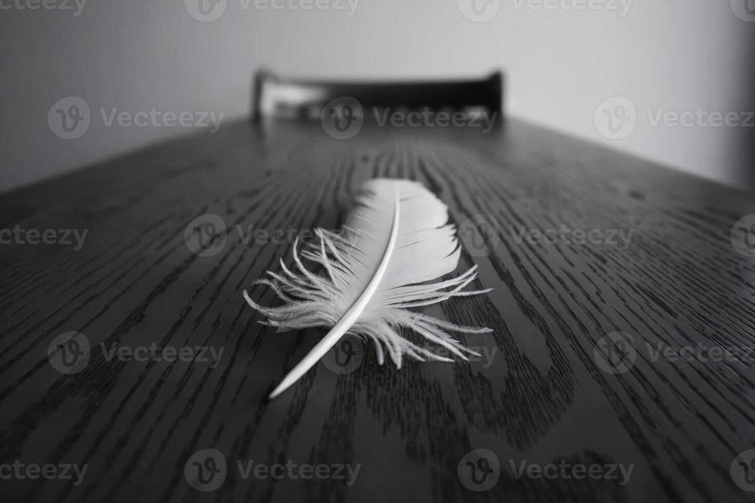 Close-up of a single white feather on a dark wooden table. photo