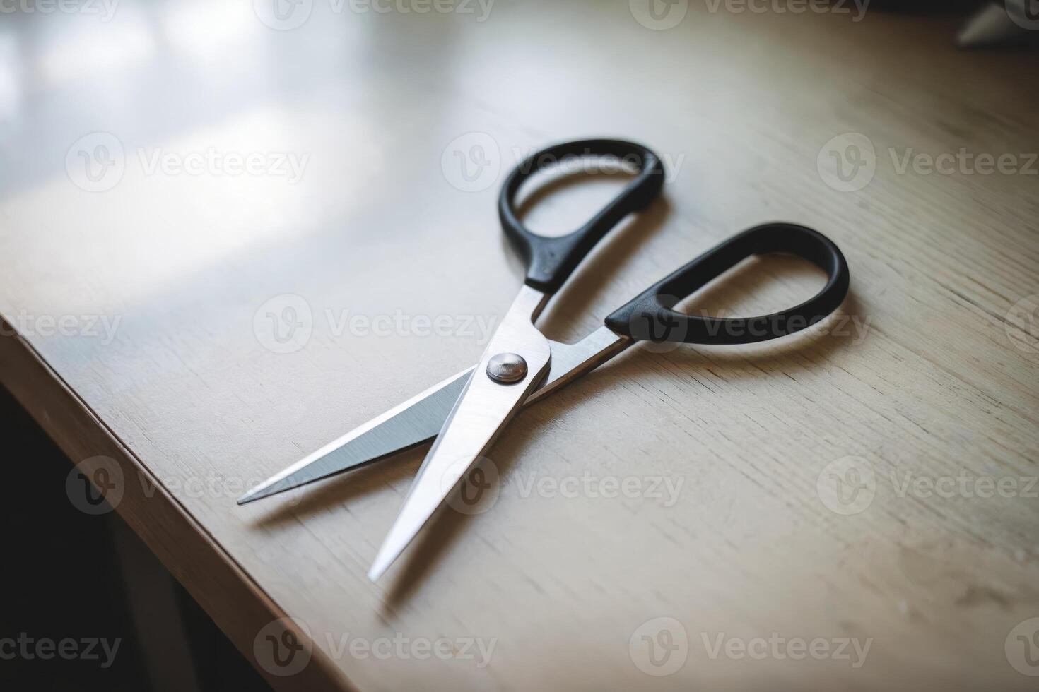 A pair of open scissors on a wooden desk, ready for use. photo