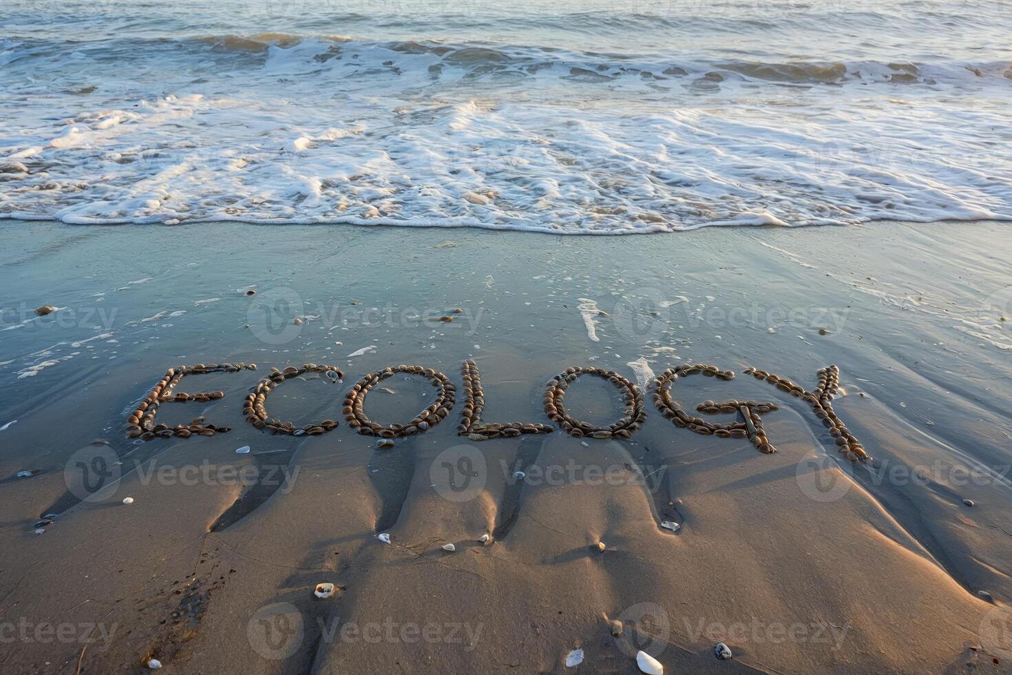 Ecology written in stones on a sandy beach with waves in the background. photo