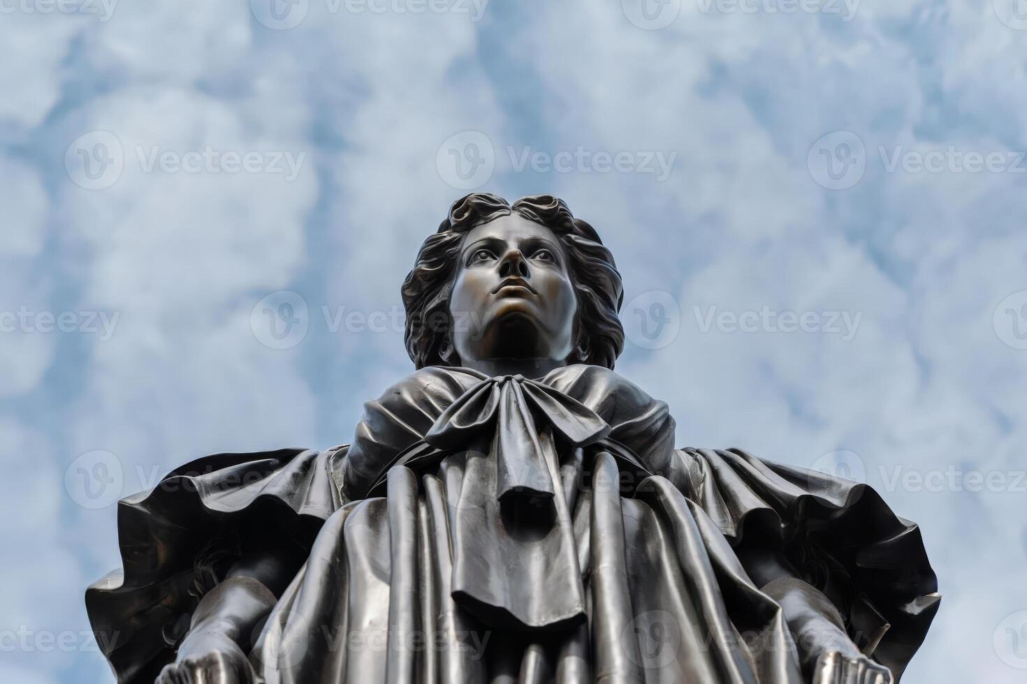 Low-angle shot of a historical statue against a cloudy sky. photo