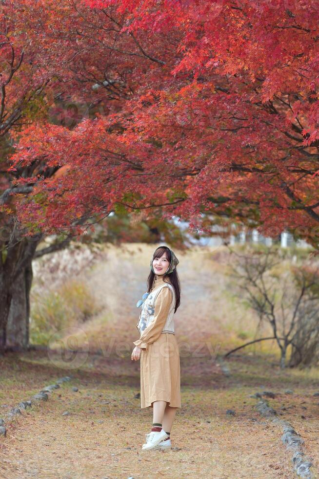 Asian woman in casual dress enjoys the beauty of fall in Japan, sharing smiles, selfies, and scenic views by the lake near Mount Fuji. A cheerful holiday portrait capturing the essence of joy. photo
