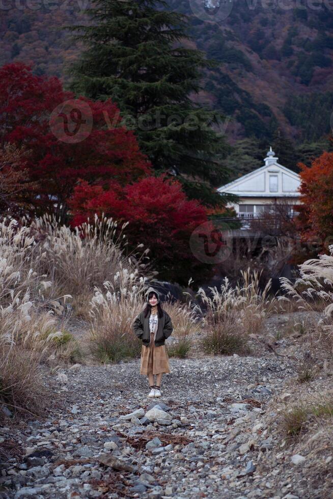 Asian woman in casual dress enjoys the beauty of fall in Japan, sharing smiles, selfies, and scenic views by the lake near Mount Fuji. A cheerful holiday portrait capturing the essence of joy. photo