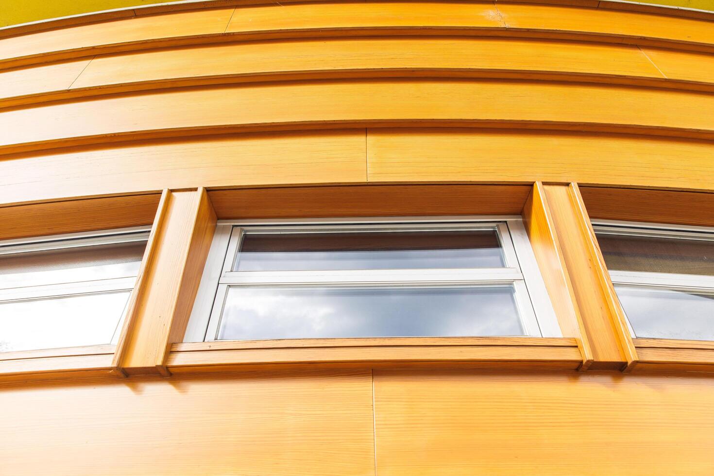 Curved modern wooden facade with geometric design and rectangular windows, contemporary architecture concept photo