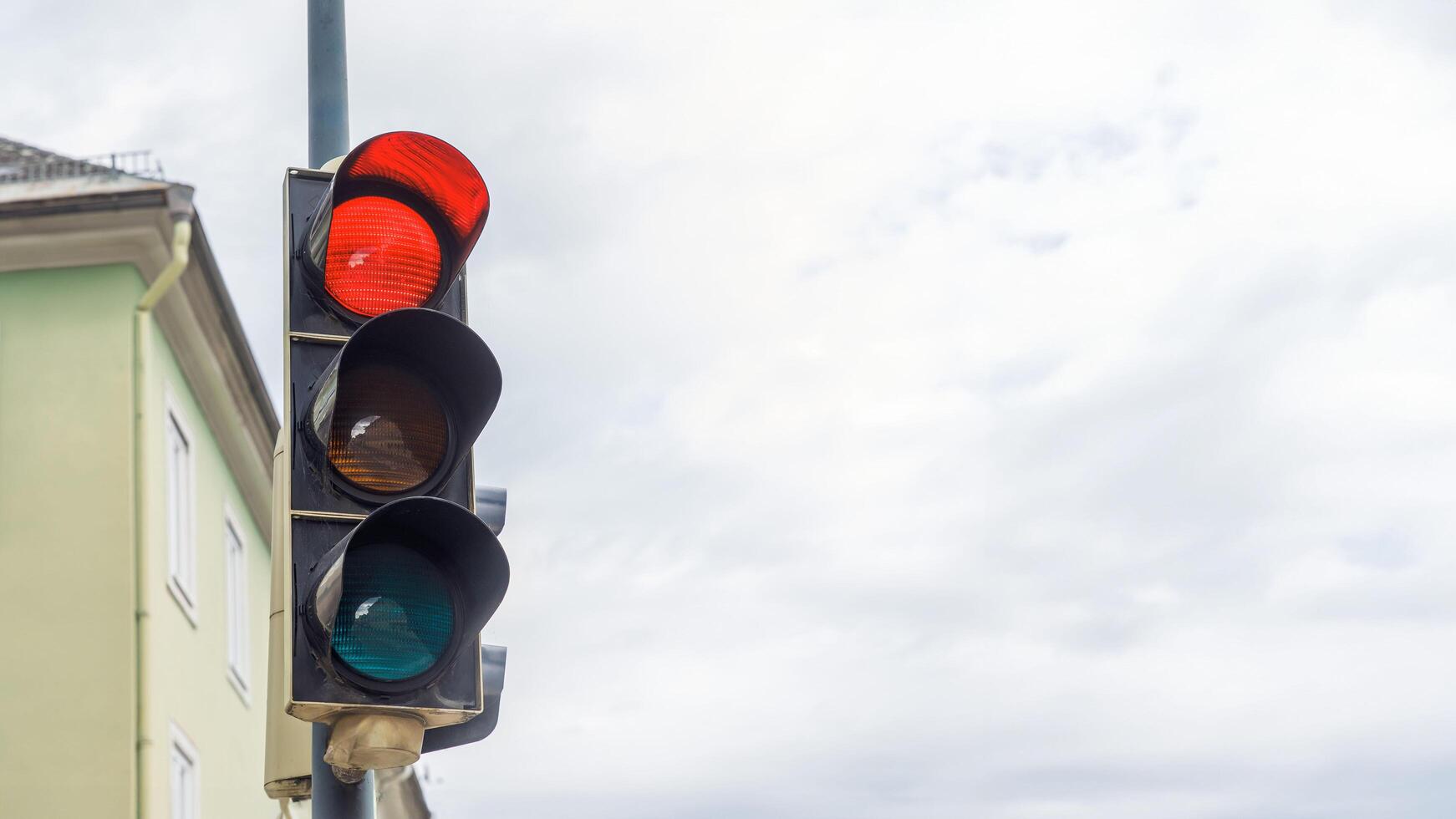 Traffic light with red, yellow, green signals at cloudy sky intersection, urban street safety concept photo