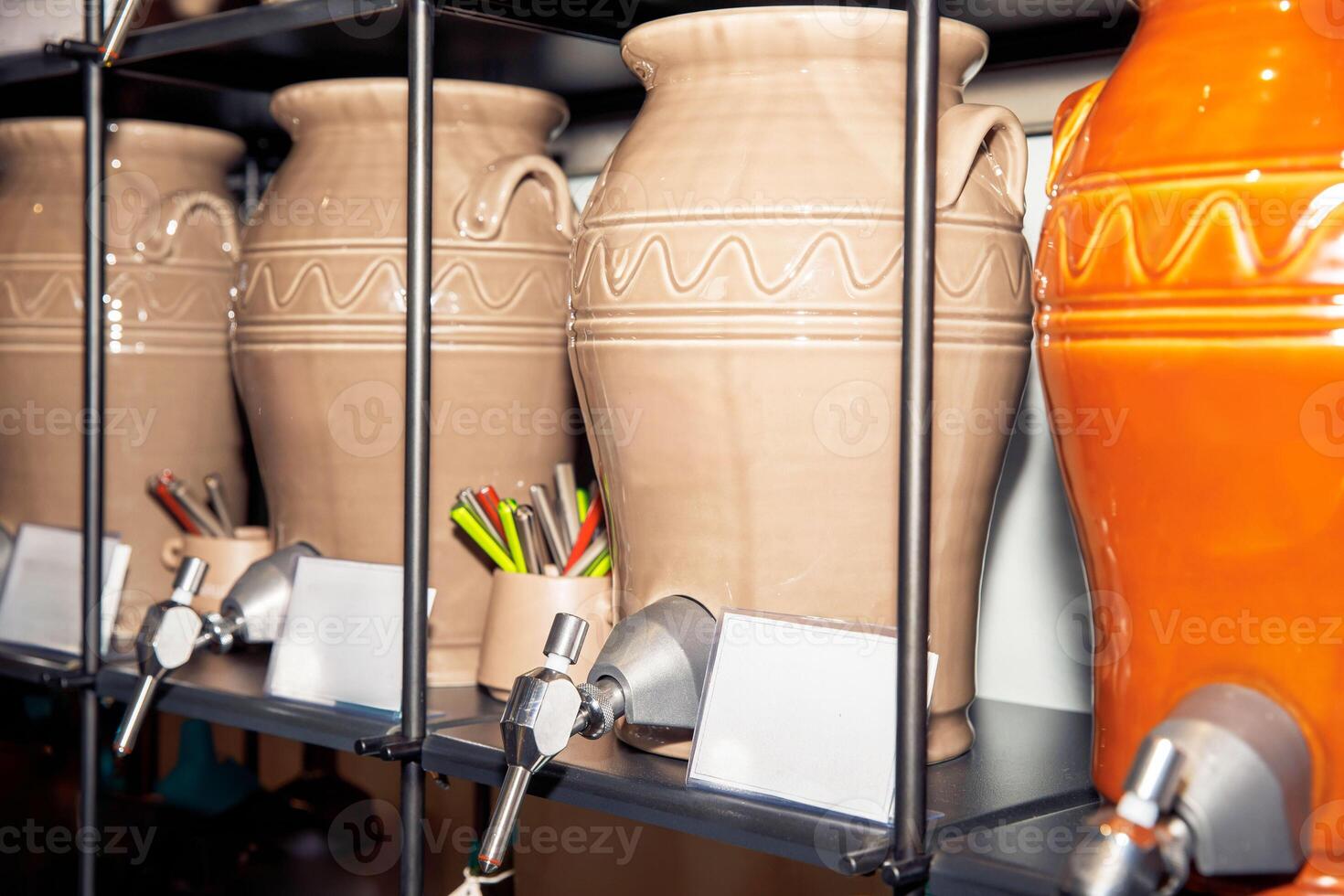 Earthenware jars with spigots on a shelf, kitchen utensils inside, various colors, storage containers concept photo