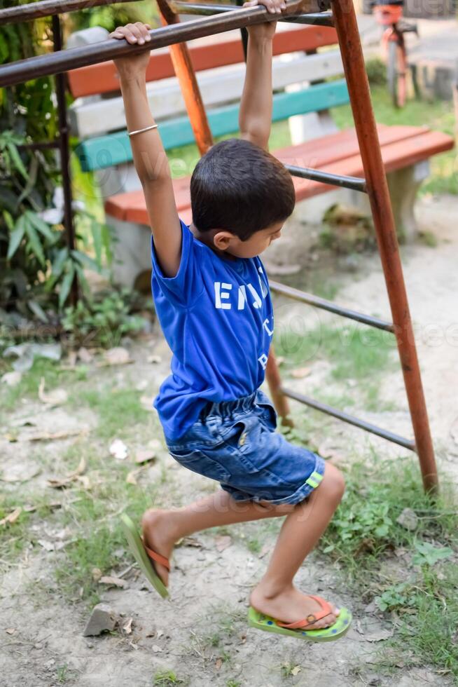 Asian boy doing routine exercise in society park during the morning time. Cute little kid exercise and gym to keep himself fit for life. Child exercise outdoor shoot photo