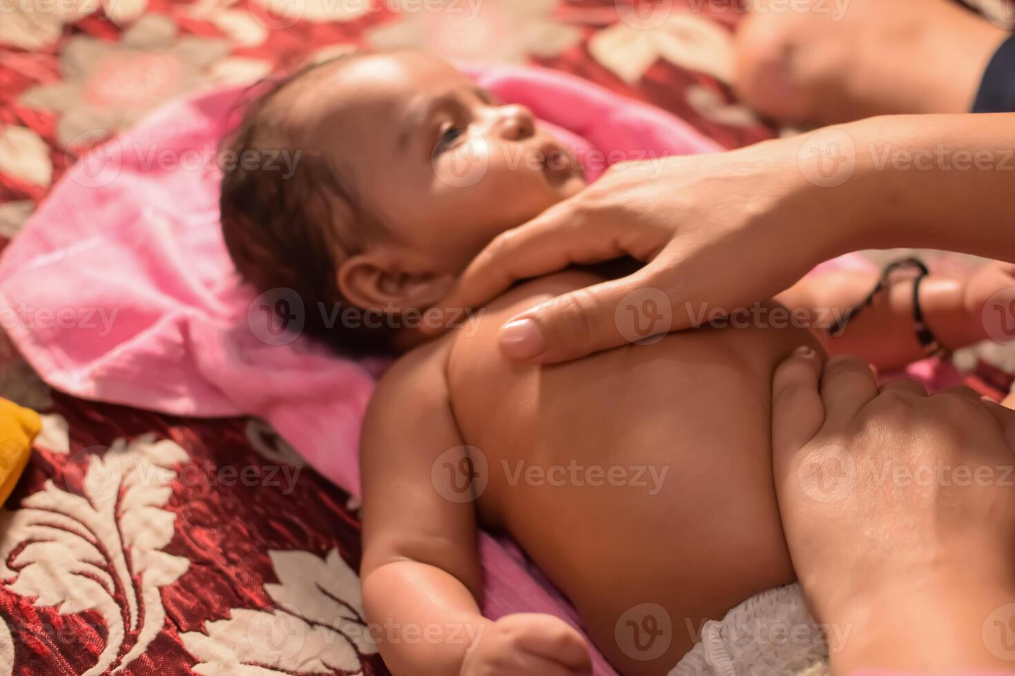 10 Months cute little Indian boy doing oil massage at home by his mother, cute little boy enjoying during oil massage, little toddler enjoying healthy massage by mother photo