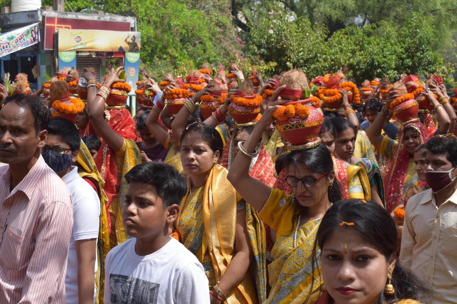 New Delhi, India July 25 2024 - Women with Kalash on head during Jagannath Temple Mangal Kalash Yatra, Indian Hindu devotees carry earthen pots containing sacred water with a coconut on top photo