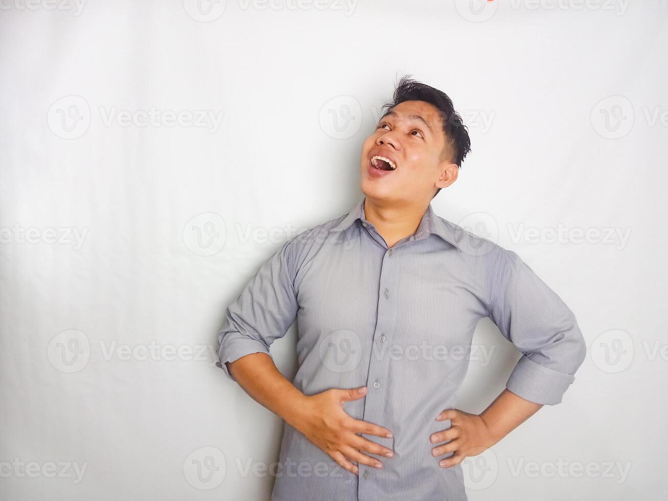 Young Asian man touching his belly with relieved expression. wearing grey shirt isolated on white background photo