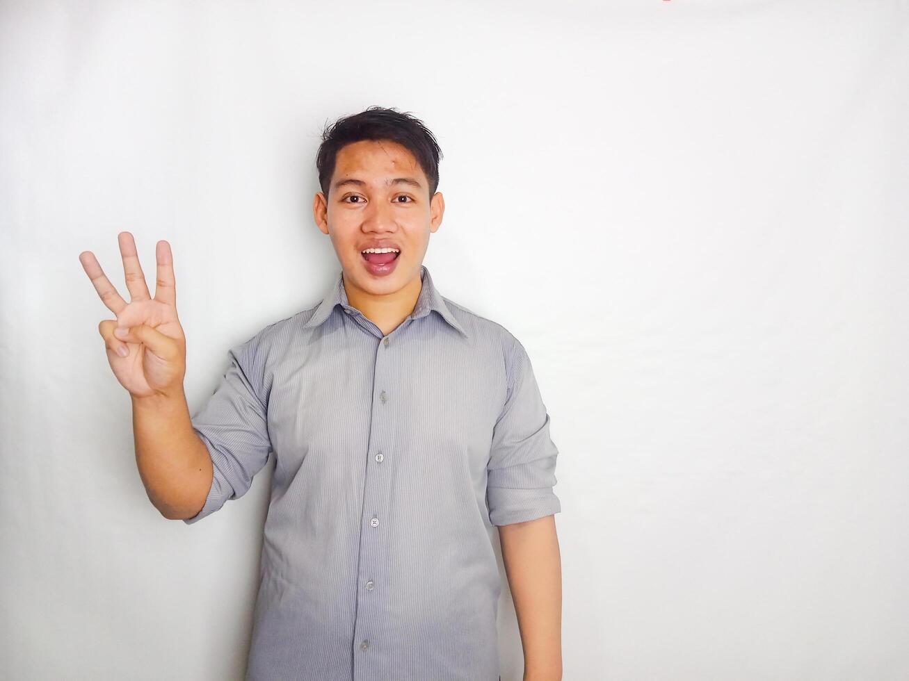 Adult Asian man smiling happy while standing and give 1,2,3,4,5 sign wearing grey shirt isolated on white background photo