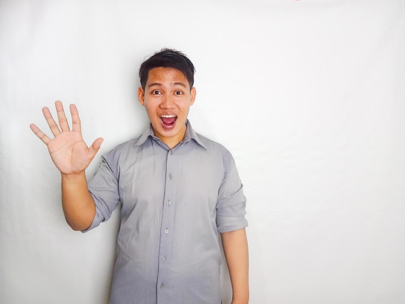 Adult Asian man smiling happy while standing and give 1,2,3,4,5 sign wearing grey shirt isolated on white background photo