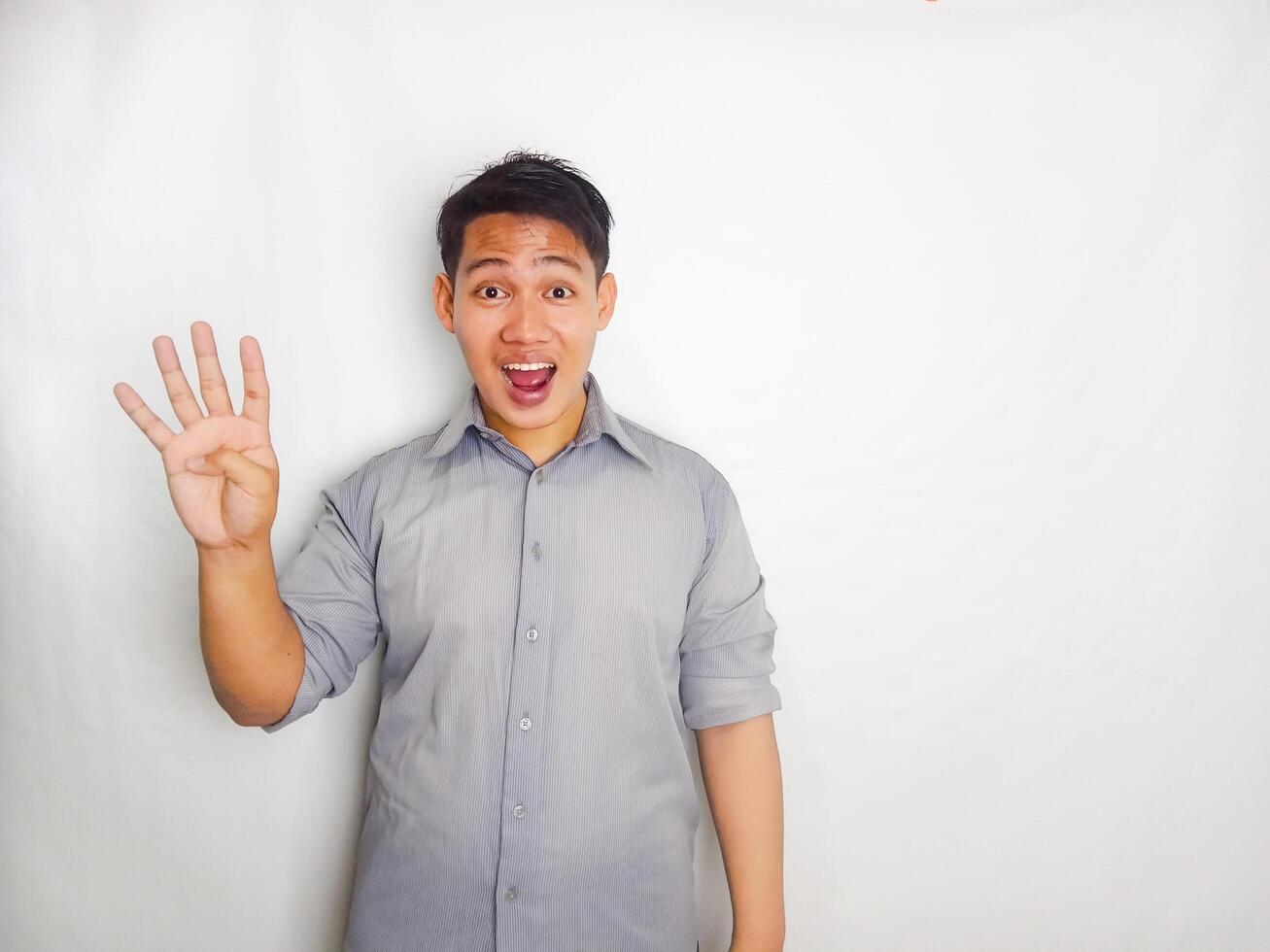 Adult Asian man smiling happy while pointing and give OK sign. wearing grey shirt isolated on white background photo
