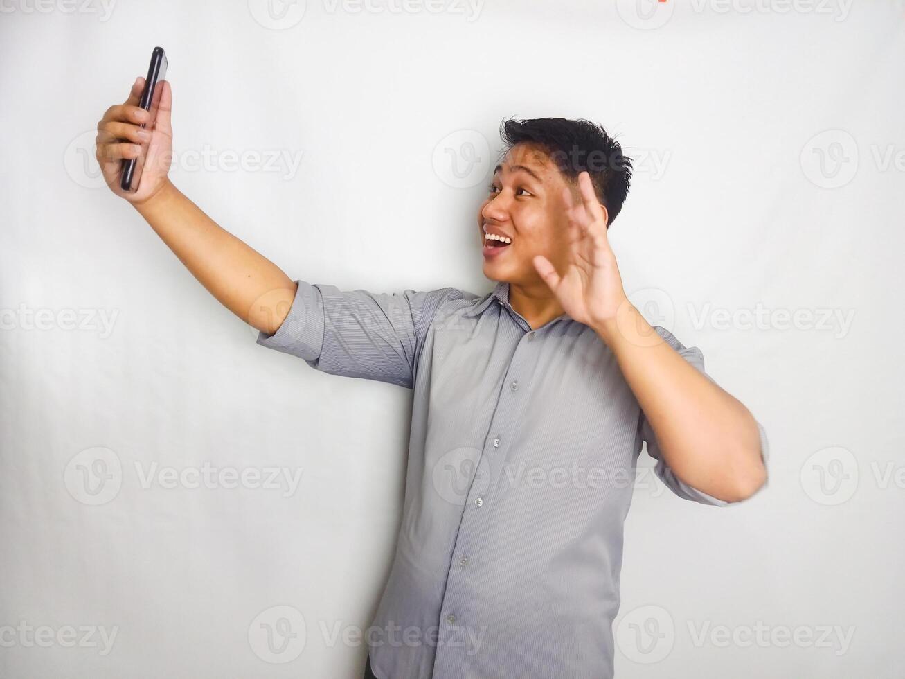 Young Asian man showing hallo and happy when doing call. wearing grey shirt isolated on white background photo