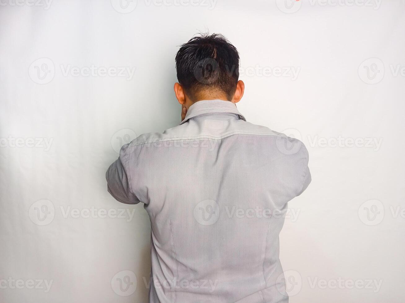 Back view of a man grabbing his head showing stress gesture wearing grey shirt isolated on white background photo