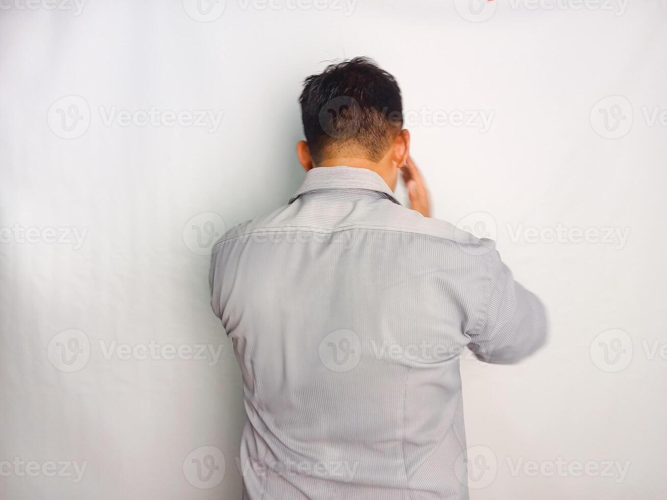 Back view of a man grabbing his head showing stress gesture wearing grey shirt isolated on white background photo