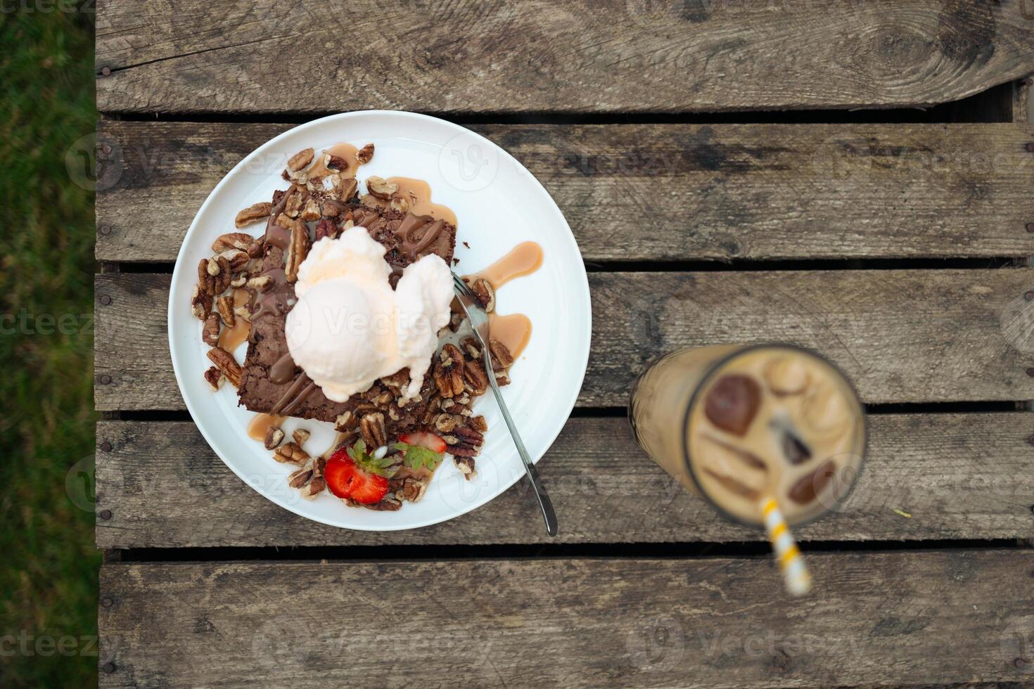 Basic homemade brownie or chocolate cake. Scoop of ice cream on a fresh stack of fresh brownies. Cold brew latte with milk and ice. photo