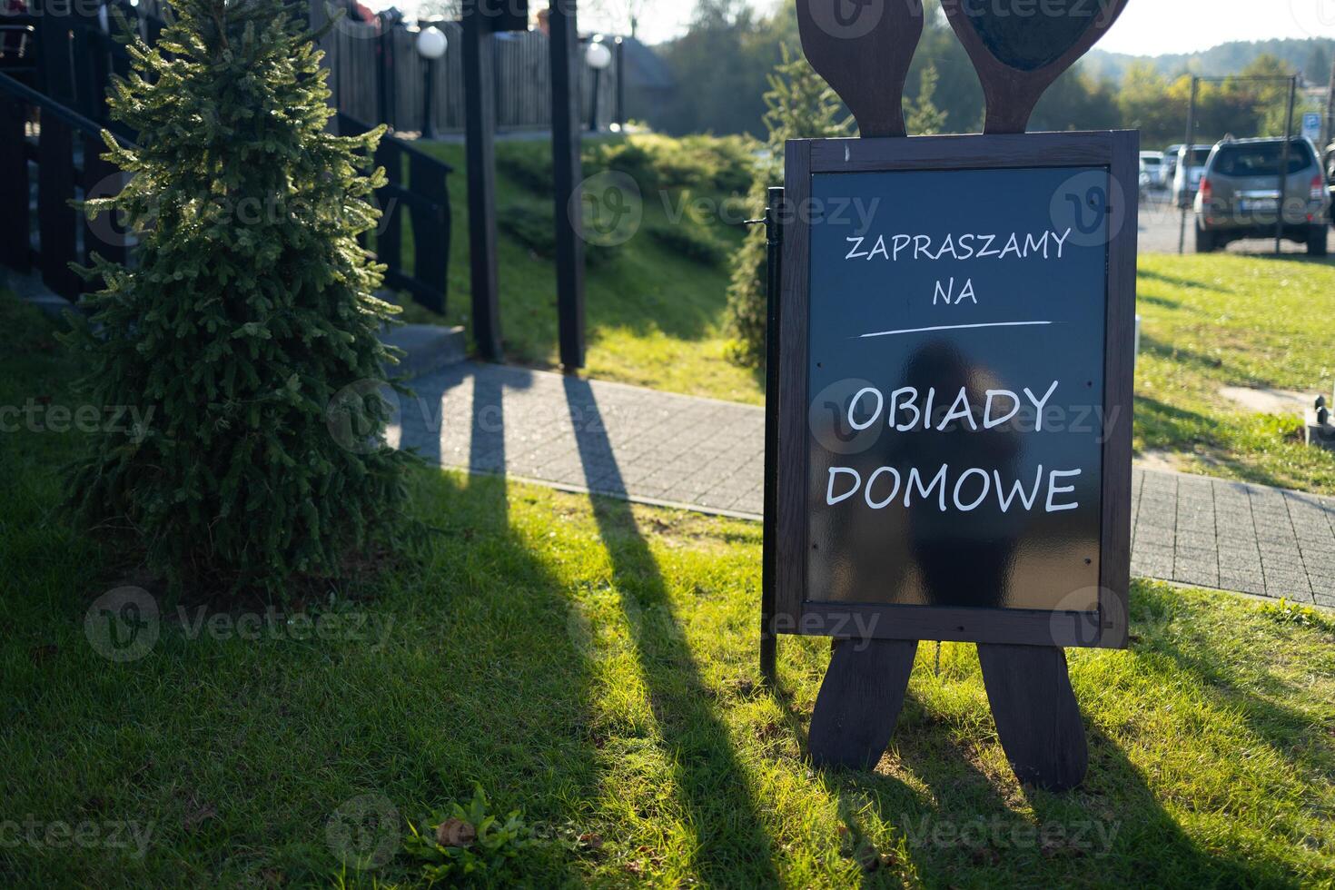 Outdoor advertising stand with menu against a rustic wooden background. Blank white template of a freestanding sandwich board at a farm gate. photo