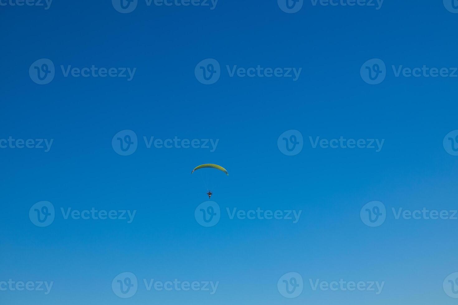 Alone paraglider flying in the blue sky against the background. Paragliding into a beautiful sky alone photo