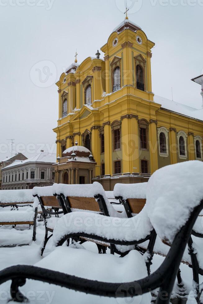 Winter scene with the St. George's Cathedral from the Union Square. Benches covered in snow. photo