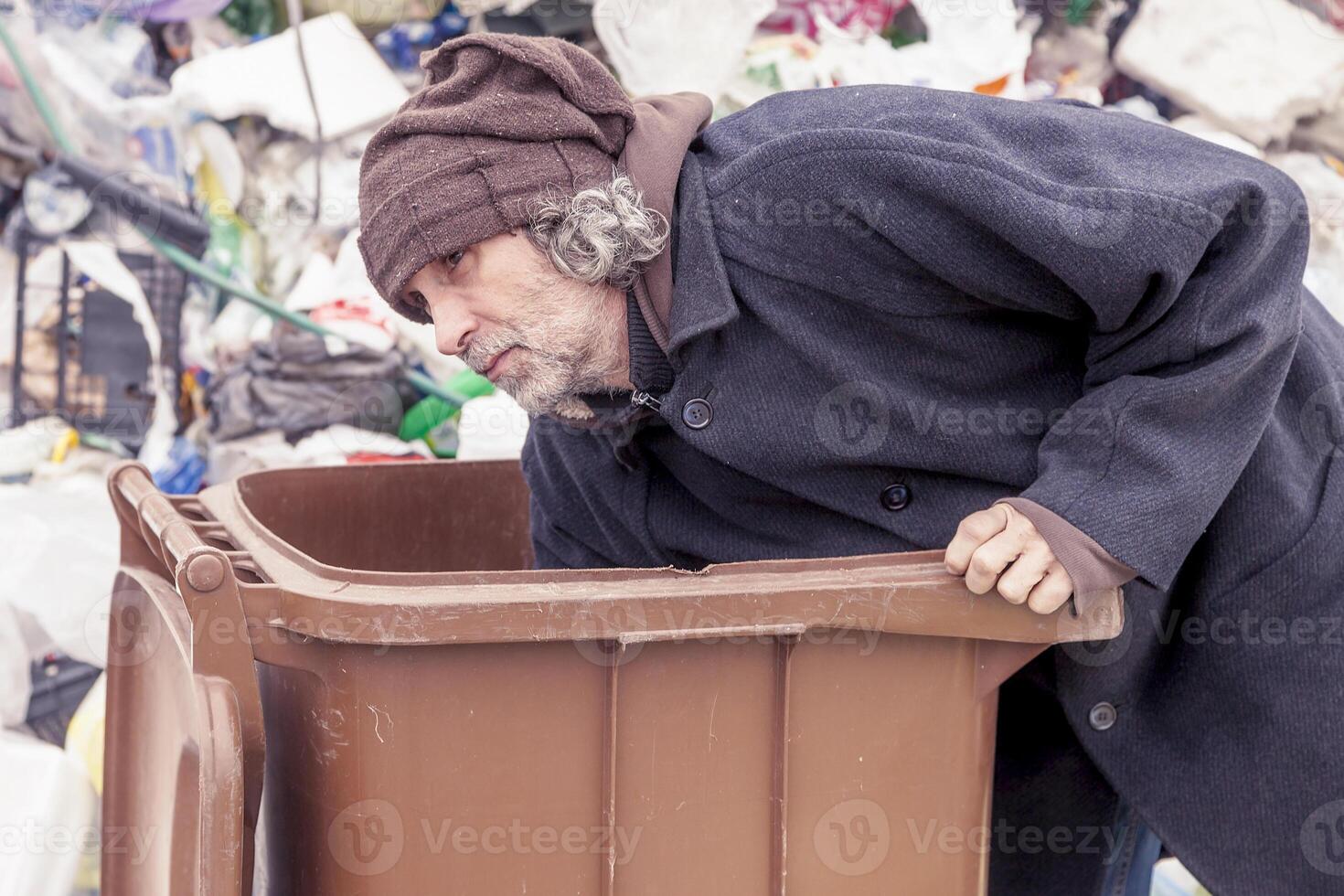 homeless rummages in the dustbin of landfill photo