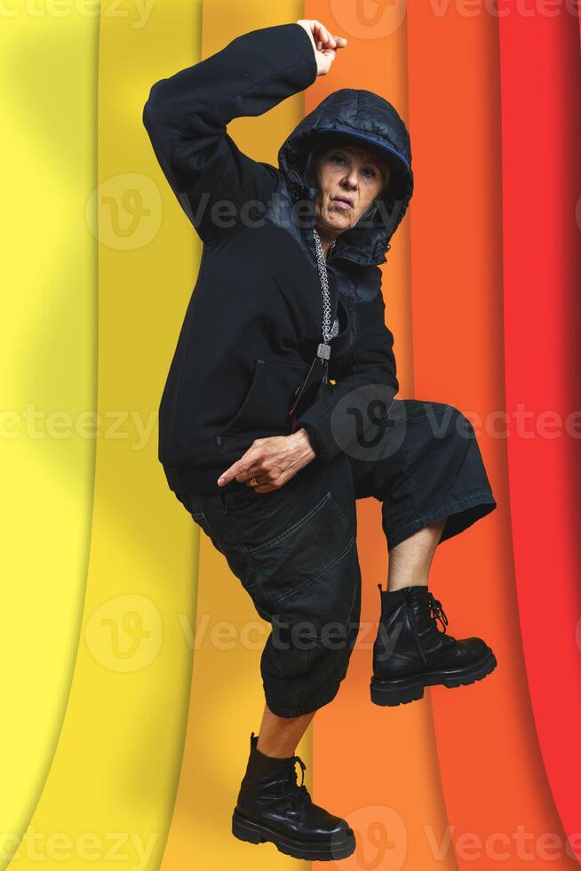 beautiful middle aged woman in black sweatshirt posing like a rapper in aggressive attitude on colorful background photo