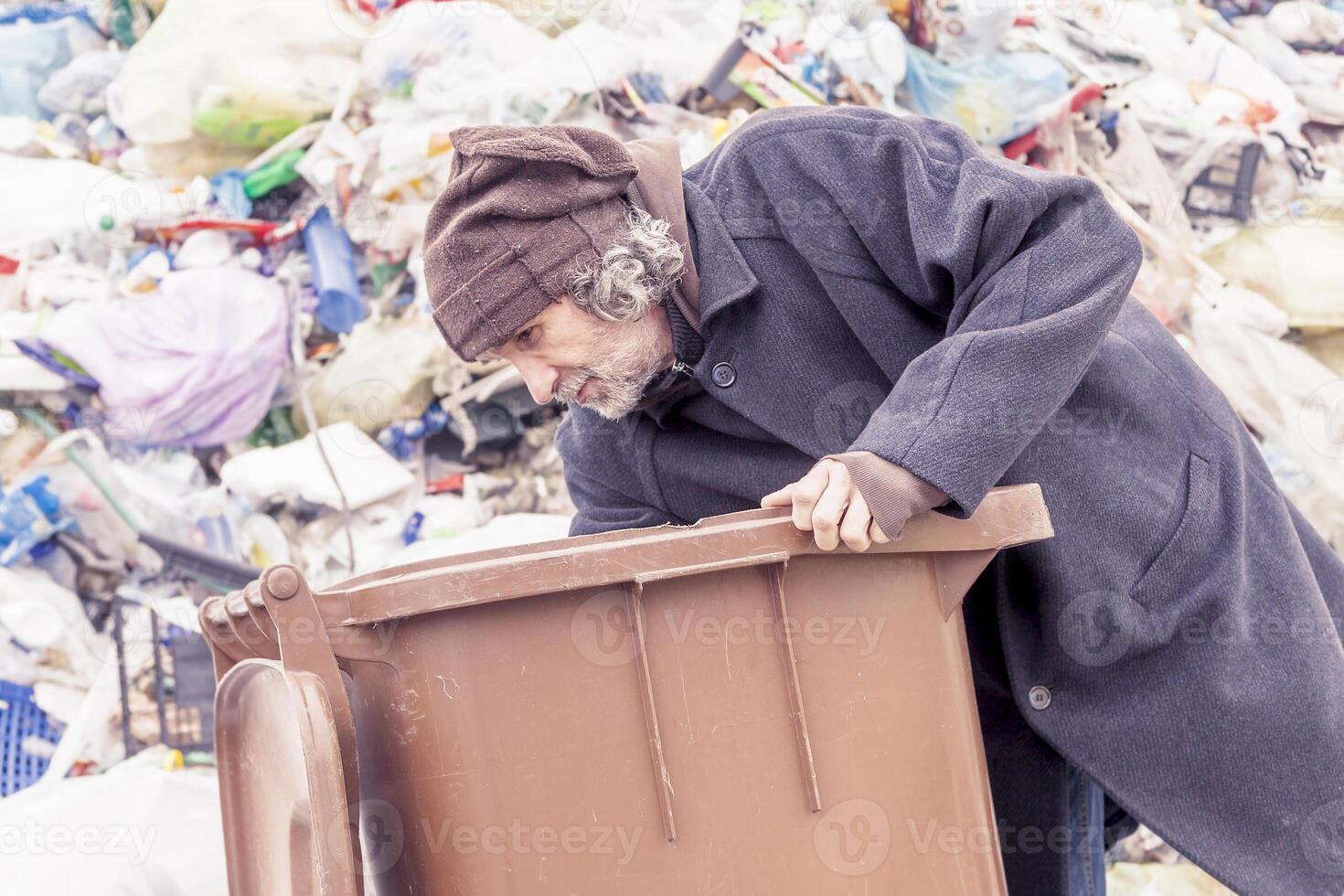 homeless rummages in the dustbin of landfill photo