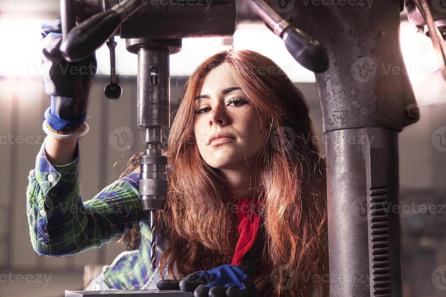 portrait of pretty girl at work on industrial drilling machine photo