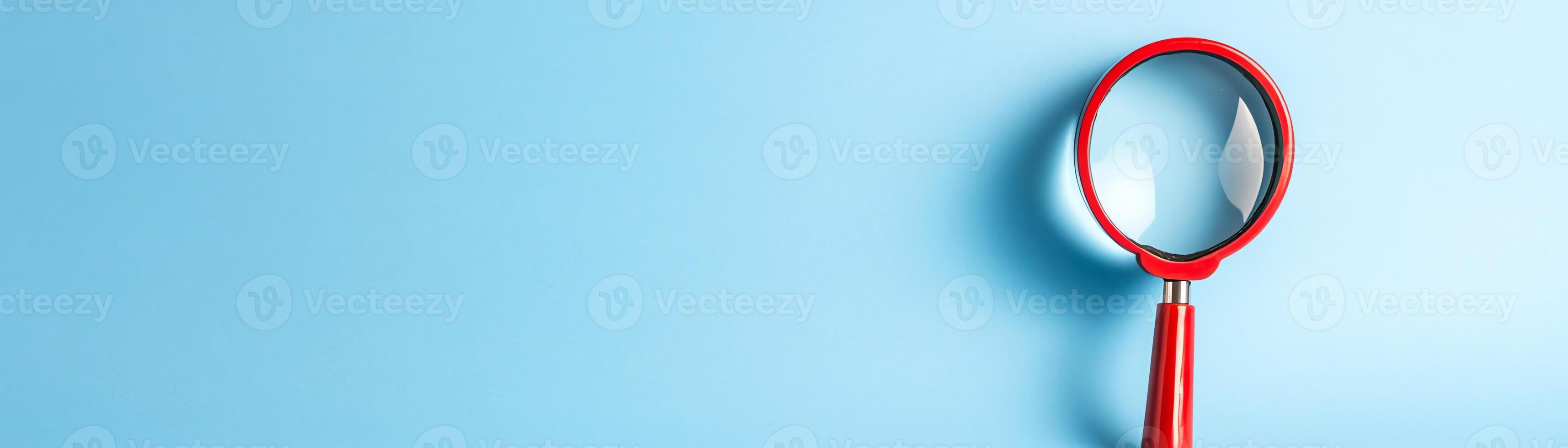 Close-up of a red magnifying glass on a light blue background. The image represents exploration, search, and discovery with simplicity and clarity. photo