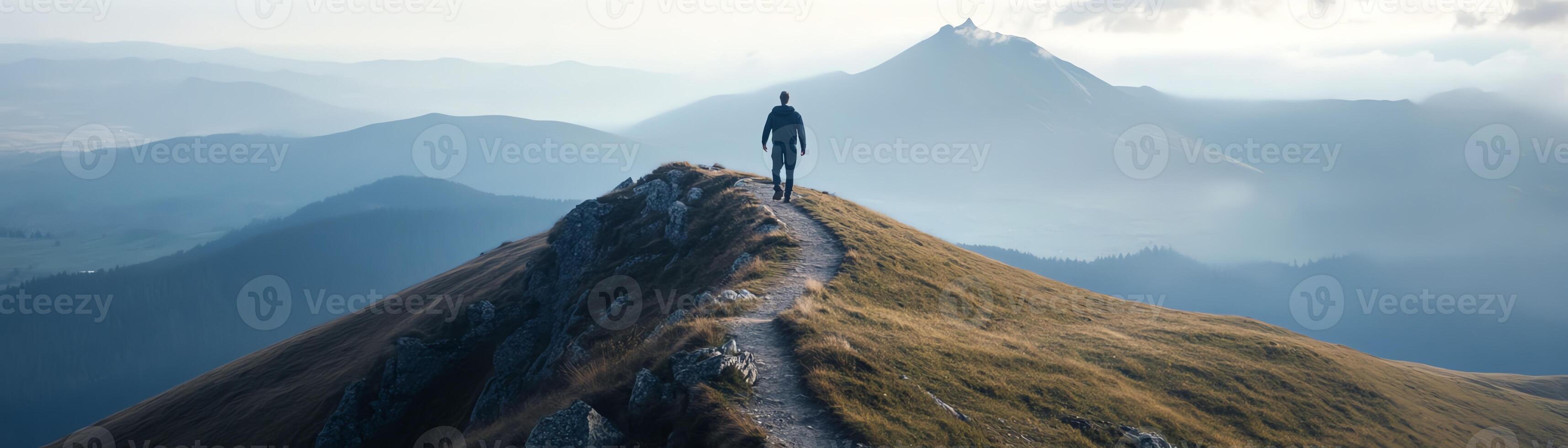 A lone hiker stands on a mountain trail, surrounded by mist and scenic mountain peaks, embracing the beauty of nature and adventure. photo