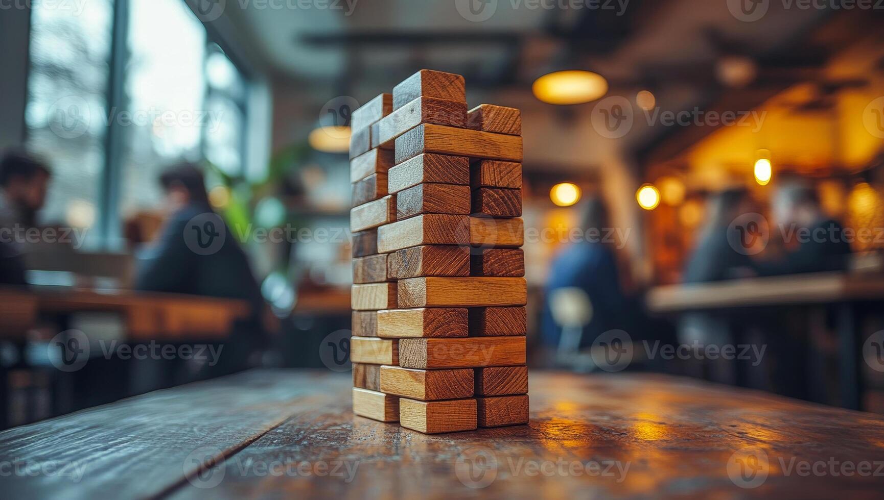 A stack of wooden blocks on a table in a restaurant. The blocks are arranged in a pyramid shape, and the scene is set in a busy restaurant with people sitting at tables and chairs photo