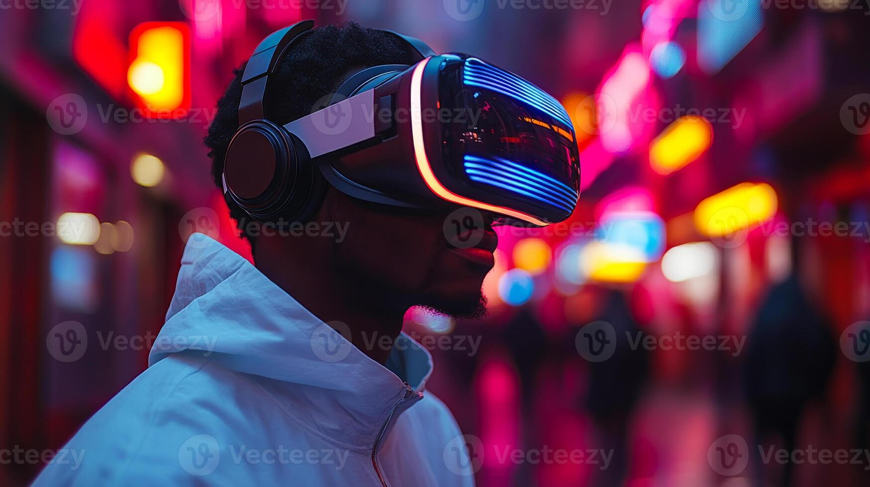 A man wearing a white jacket and black headphones is looking at a virtual reality display. The scene is set in a city at night, with neon lights illuminating the area photo