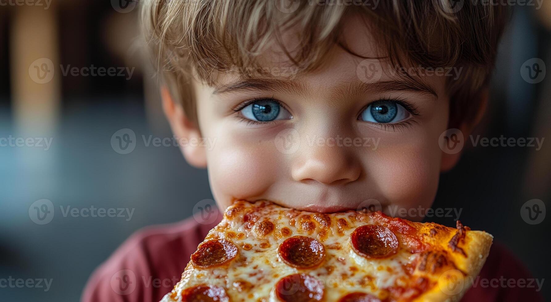 A young boy is eating a slice of pepperoni pizza. He has a big smile on his face as he enjoys his meal photo