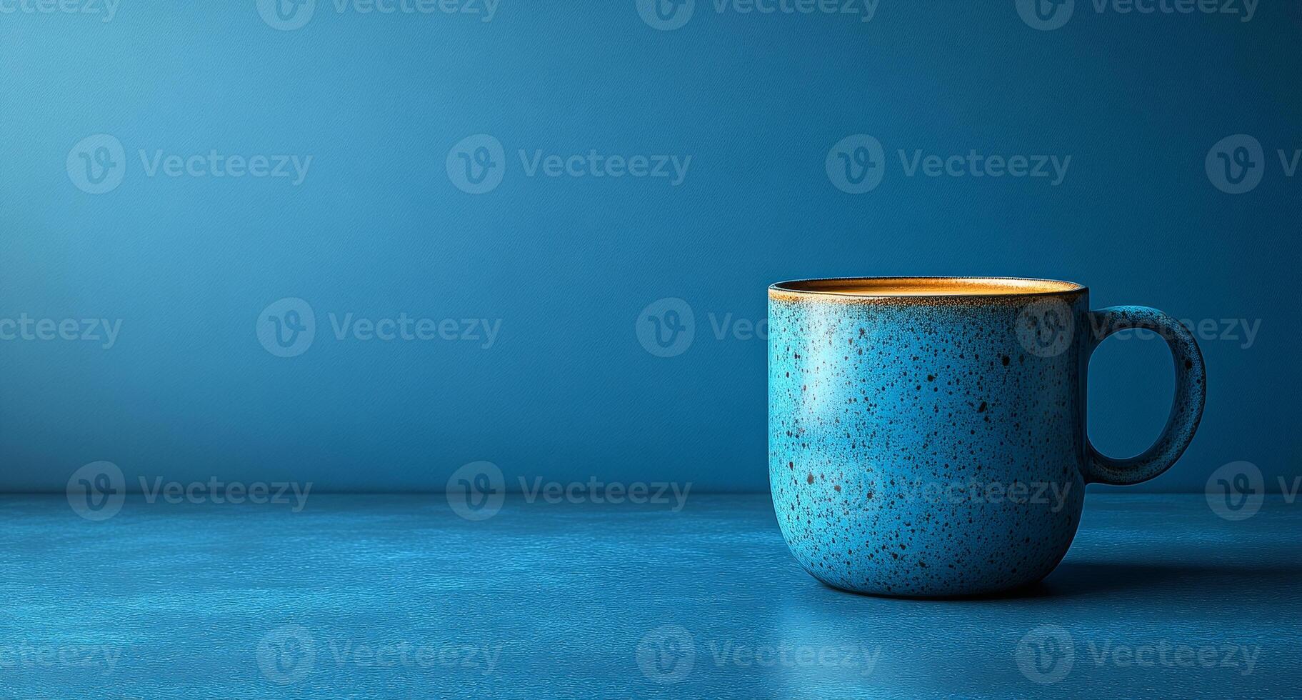 A colorful blue mug filled with coffee sits on a smooth surface against a calm blue backdrop, creating a soothing atmosphere. photo