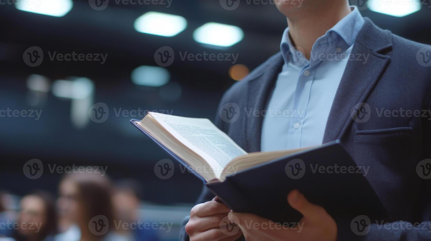 A Man in a Suit Reads a Book While Standing in a Crowd photo