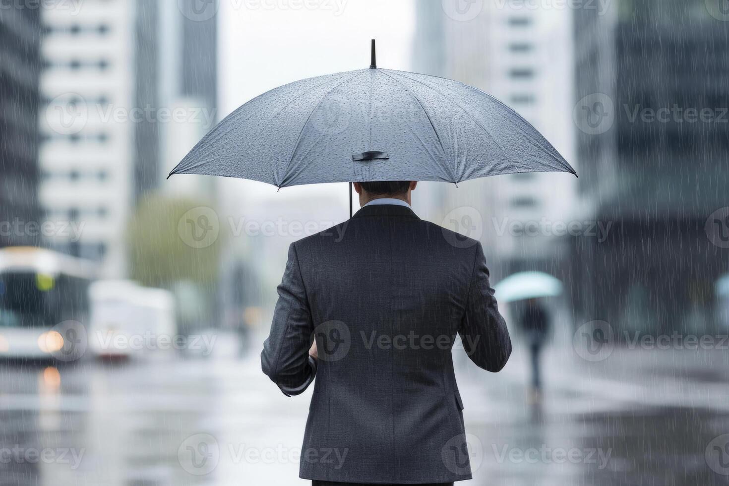Man holding a black umbrella during a rainy day in the city photo