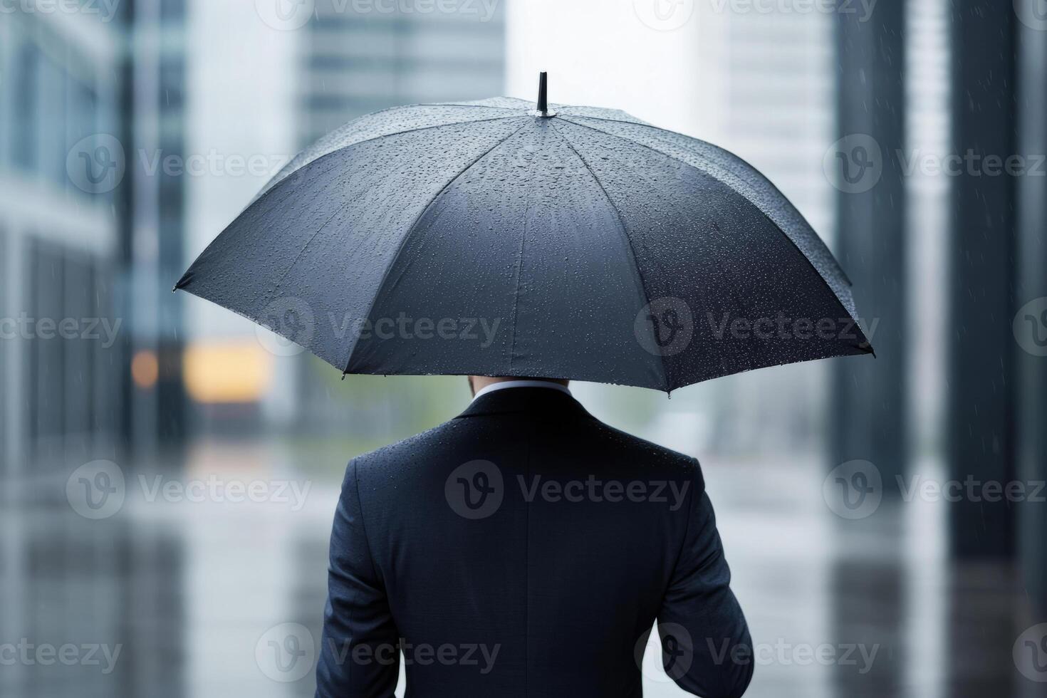 Man holding a black umbrella during a rainy day in the city photo