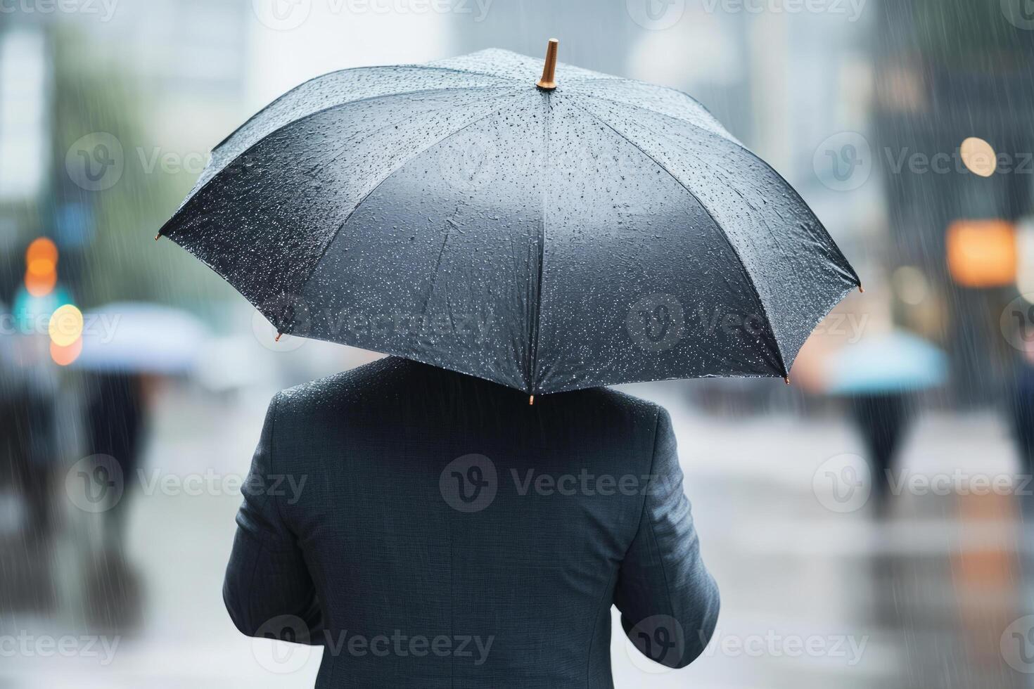 Man holding a black umbrella during a rainy day in the city photo