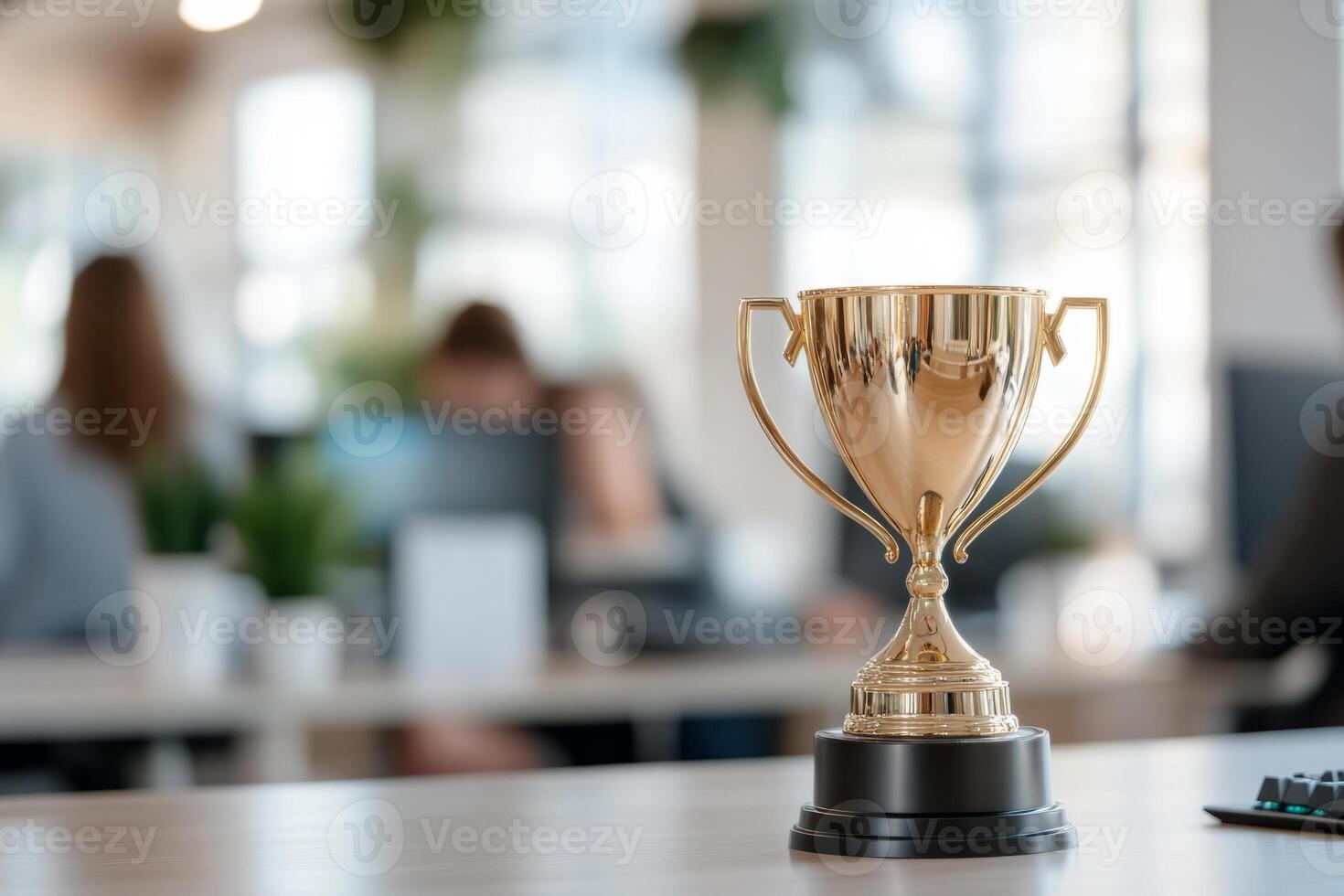 Golden trophy on a desk in a modern office environment with computers in the background photo