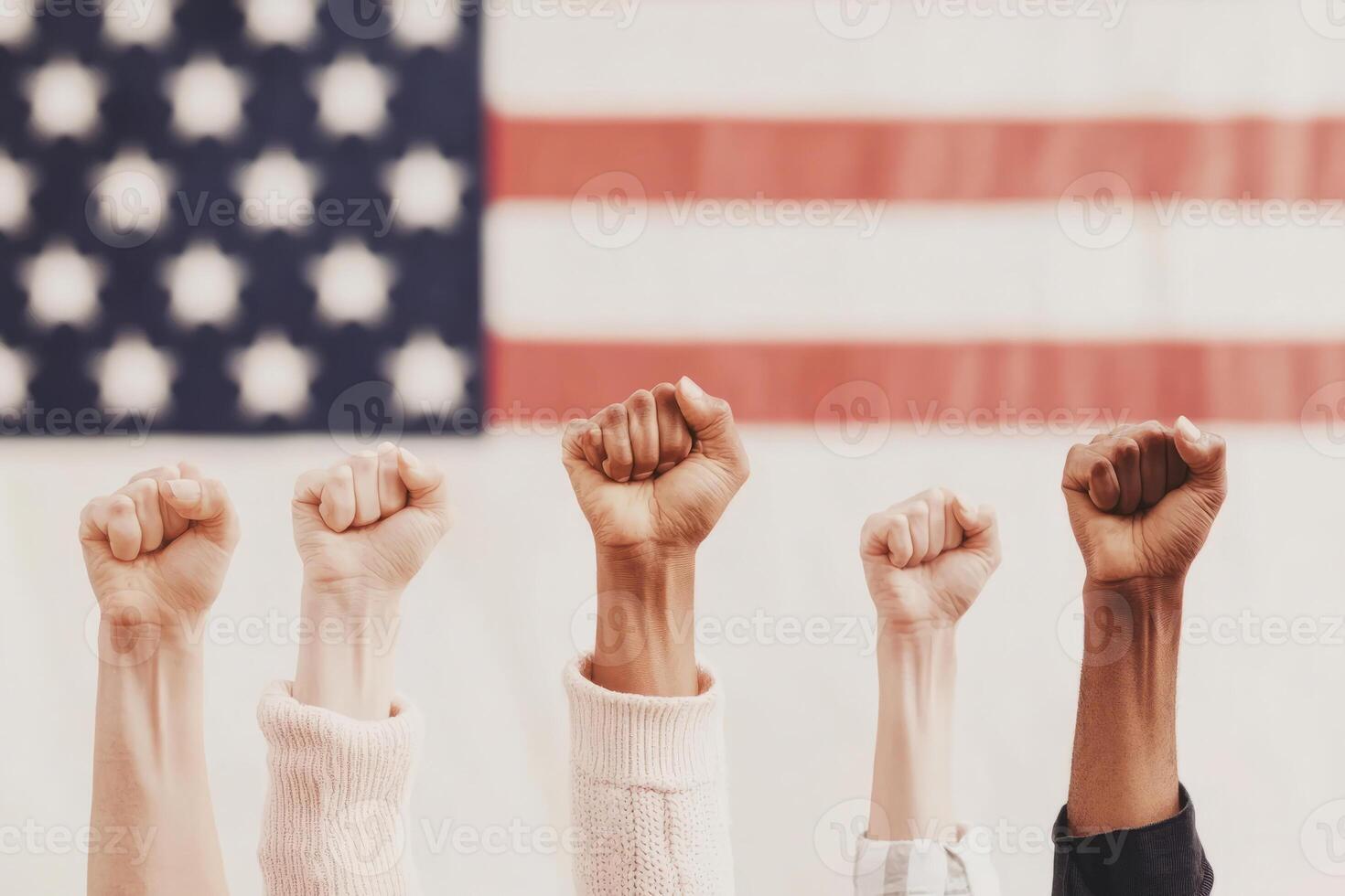 Hands with raised fists show solidarity and unity in front of a blurred American flag, symbolizing strength, activism, and diversity. photo