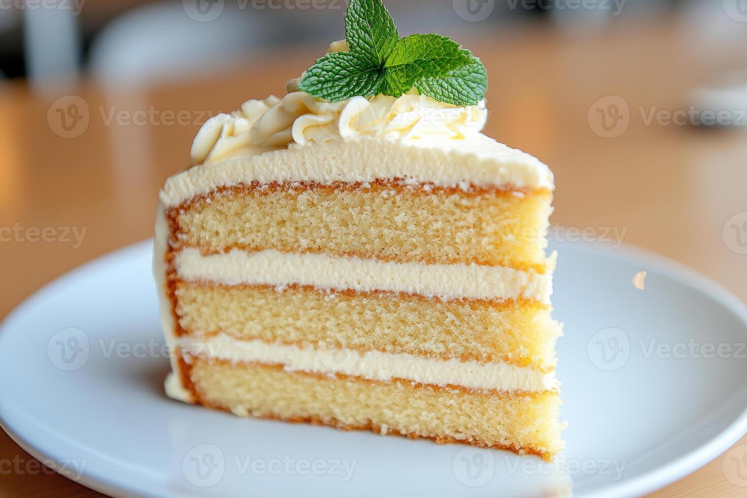 Slice of vanilla cake topped with whipped cream and a mint leaf photo