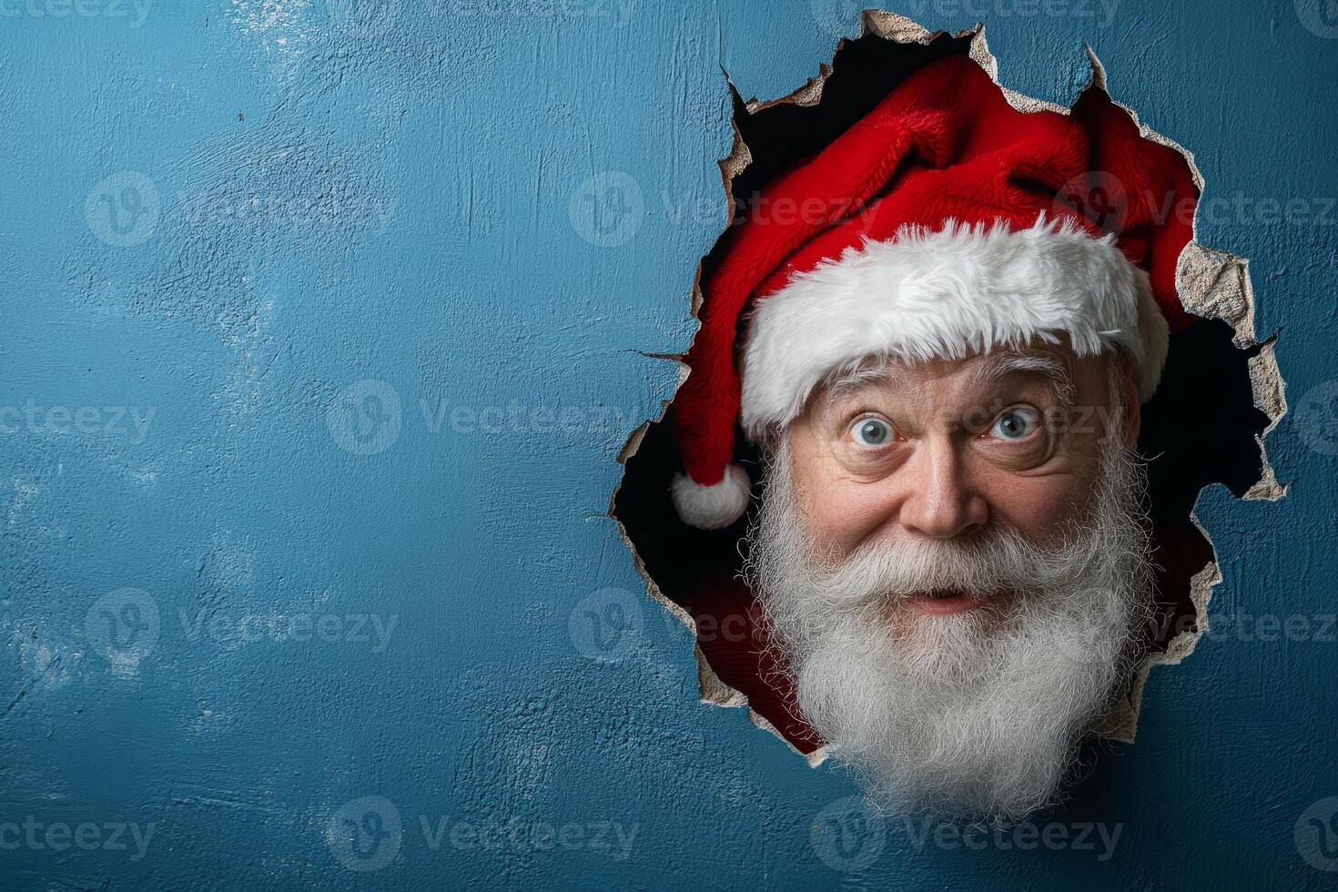 Santa Claus peeking through a hole in a blue background photo