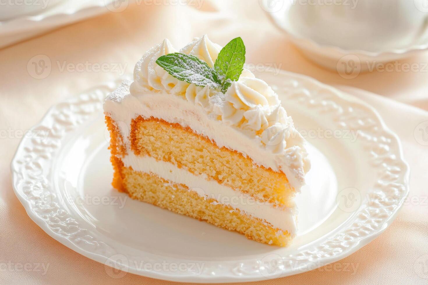 Slice of vanilla cake topped with whipped cream and a mint leaf photo