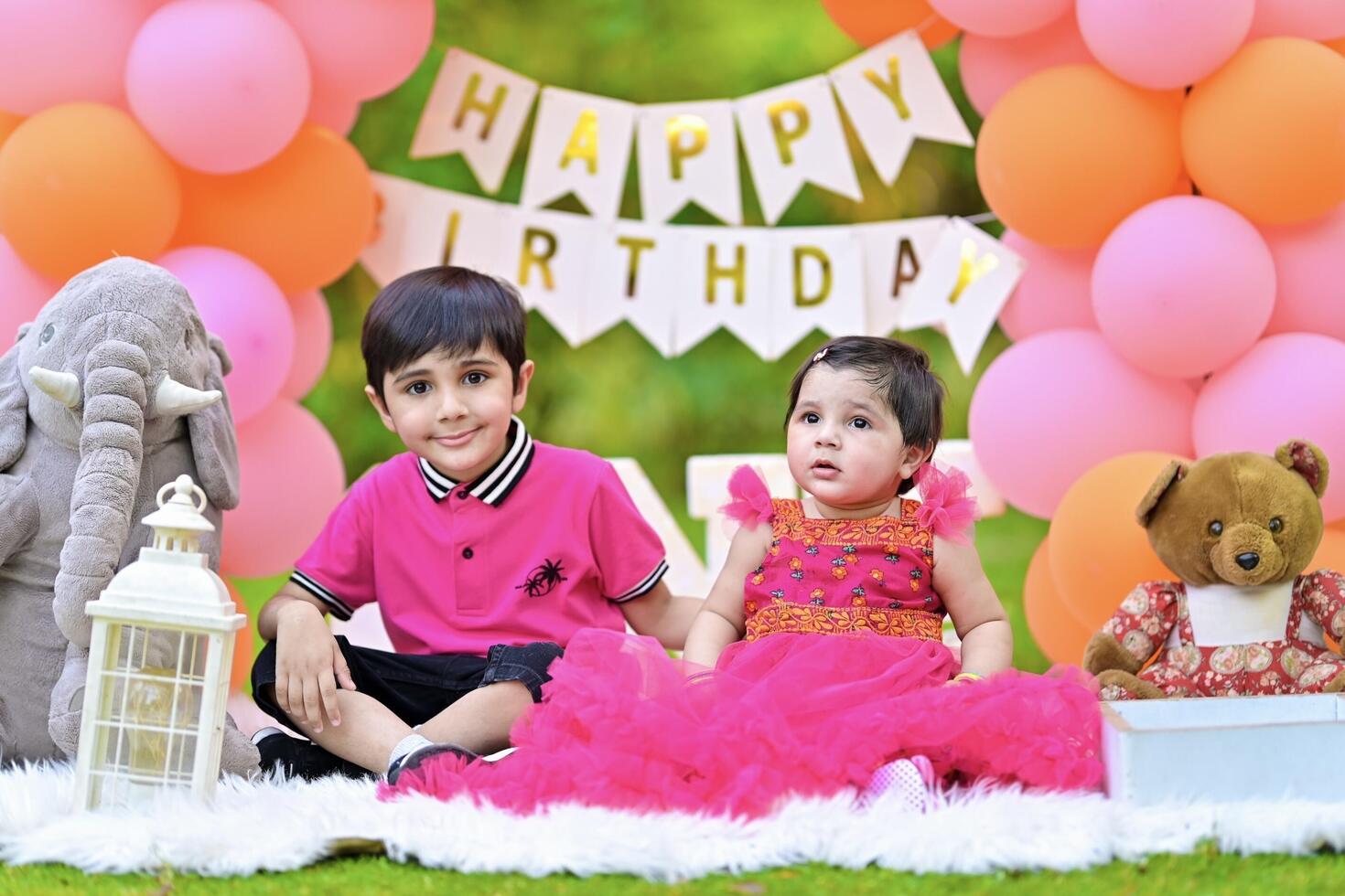 Two children in pink dresses sitting on a blanket with balloons photo