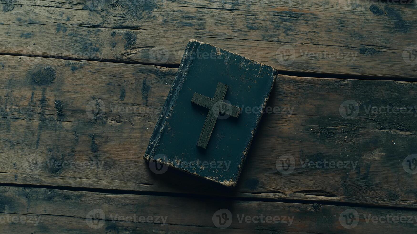 Cross placed on an old book resting on a rustic wooden table with plenty of empty space photo