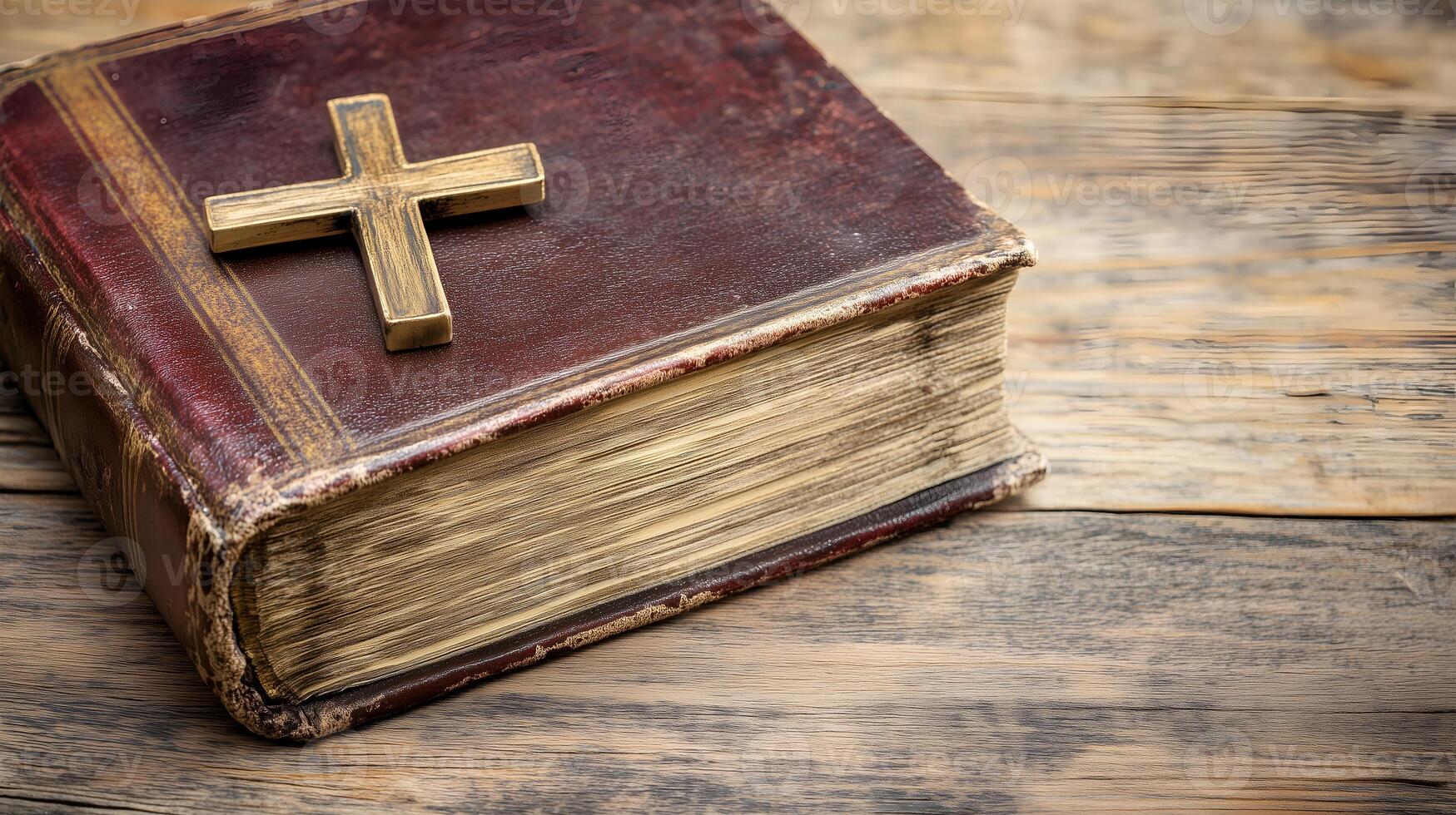 A weathered book rests on a wooden surface, adorned with a golden cross as a symbol of faith photo