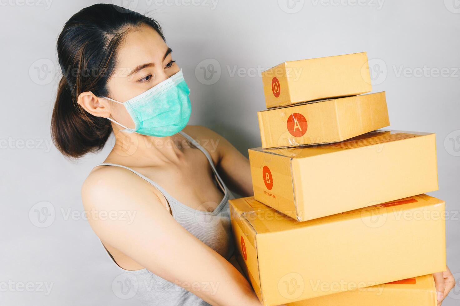 Asian woman wearing mask and holding parcel boxes for delivery. The COVID-19 outbreak, has had a positive impact on the e-commerce sector as the virus has created a new normal in online shopping. photo